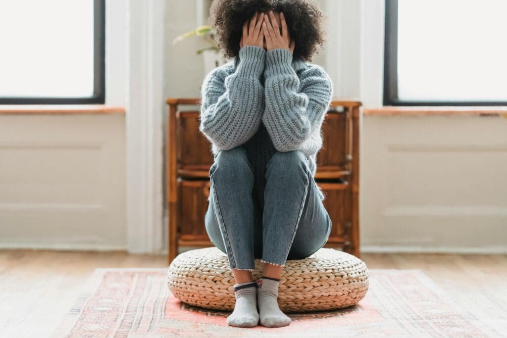 woman sitting on a futon with hands on her face frustrated because of her toxic relationship